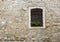 Wooden window with flowers on windowsill on stone wall of ancient house