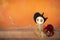 Wooden witch doll and black spider over blurred orange backgroun