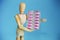 Wooden yellow mannequin holds pink medical pills