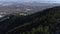 Woodland mountain landscape with large city behind it from a drone