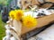 Woodpile of birch firewood. Bouquet of yellow dandelions on the fence. Preparation of wood for the oven