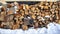 Woodpile of firewood in the snow closeup