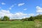 The woods Creek trail, the road. Village. Deciduous trees, young foliage and grass. Cloudy sky