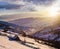 Woodshed on the hillside in winter mountains at sunset