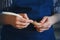 A woodworker in a blue apron is holding a handmade wooden spoon