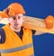 Woodworker concept. Carpenter, woodworker, labourer, builder carries wooden beam on shoulder. Man in protective gloves