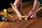 Woodworker connects the wooden planks with a screwdriver and screw. Closeup the hands of the master at work. Working environment