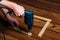 Woodworker drills a hole with an electric drill in a wood board. Close up of a foreman hand at work. Working environment in a