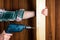 Woodworker drills a hole with an electric drill in a wood board. Close up of a foreman hand at work. Working environment in a