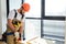 Woodworker drills hole with an electric drill in wood board. Repairman in overalls with drill