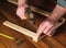 Woodworker hammers a nail into a plank with a hammer. Hands of the master close-up. Working environment in a carpentry workshop