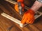 Woodworker hammers a nail into a plank with a hammer. Hands in work gloves of the master close-up. Working environment in a