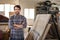 Woodworker standing with his arms crossed in a workshop