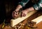Woodworker using a hand plane to clean up a wooden board. Hands of the master closeup at work. Working environment in a carpentry