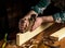 Woodworker using a hand plane to clean up a wooden board. Hands of the master closeup at work. Working environment in a carpentry