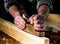 Woodworker using hand plane to clean up a wooden board. Hands of the master closeup at work. Working environment in carpentry