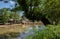 Woody riverside before stone beam bridge over river in sunny autumn