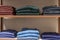 Wool jumpers in different colors on the wooden shelves of the store. New autumn winter collection. Front view