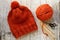 Wool orange hat, knitting needles and yarn