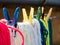 Woolen colorful threads are hanging on a clothesline with clothespins outdoors.