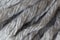 Woolen fluffy threads or tassels from scarf, macro. Soft grey merino wool backdrop, closeup. Autumn and winter flat lay.