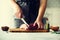 Wooman hands cutting beef meat on wooden chopping board, rosemary, oil, salt, pepper. Girk cooking pork meat on white