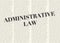 The word ADMINISTRATIVE LAW written and highlighted in front of blurred text columns on background of light yellow color
