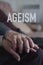 Word ageism and old man and woman holding hands