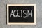 Word `Ageism` written on a small blackboard with wooden frame