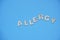 The word Allergy is made of wooden letters on blue background. The flat lay concept of the disease of allergies