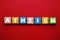 Word Atheism made of wooden cubes with letters on red table, top view