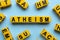 Word Atheism made of yellow cubes with letters on light blue background, flat lay
