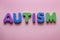 The word autism and multi-colored letters on a pink background. Autism Awareness Day. Autism Spectrum Disorder concept