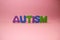 The word autism and multi-colored letters on a pink background. Autism Awareness Day. Autism Spectrum Disorder concept