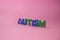 The word autism and multi-colored letters on a pink background. Autism Awareness Day. Autism Spectrum Disorder concept