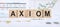 Word AXIOM made with wood building blocks on background from financial graphs and charts