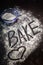 The word bake with a heart in flour dusted on table