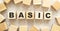 The word BASIC consists of wooden cubes with letters, top view on a light background