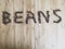 The word beans written in coffee beans on a wooden table