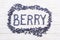 Word berry written letters with blueberries on white wooden boar