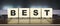 Word BEST. Wooden cubes with letters isolated on a laptop keyboard. Business Concept.