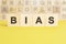 word bias is written on wooden cubes on a bright yellow surface, concept