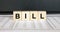 Word Bill made with wood toy blocks on financial tables
