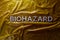 The word biohazard laid with silver letters on yellow crumpled plastic film background in flat lay composition at center
