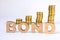 Word bond of three-dimensional letters is in foreground with growth columns of coins on blurred background. Bond concept for finan