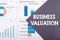 The word BUSINESS VALUATION is written on a gray background with diagrams and graphs