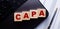 The word CAPA is written on wooden cubes on the keyboard next to the pen
