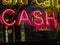 Word cash in pink neon in shop window reflected into background