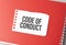 The word Code of Conduct on torn paper on red notepad