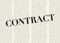 The word CONTRACT written and highlighted in front of blurred text columns on background of light yellow color